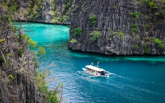 A boat glides across the crystal-clear waters of Kayangan Lake during this cruise-friendly private Coron island hopping tour A