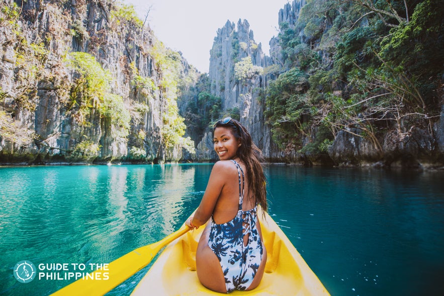 Happy female traveler kayaking along a lagoon in Coron, Palawan Happy female traveler kayaking along a lagoon in Coron, Palawan