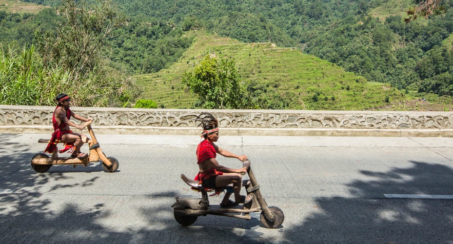 Ifugaos on their wooden scooters in Banaue, Philippines Ifugaos on their wooden scooters in Banaue, Philippines