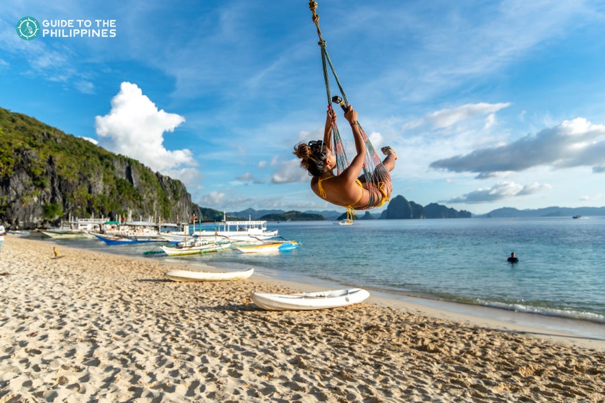 Traveler swinging and enjoying the beach in Palawan Traveler swinging and enjoying the beach in Palawan