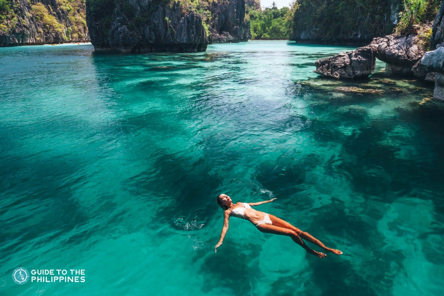 Traveler floating along a lagoon in El Nido, Palawan Traveler floating along a lagoon in El Nido, Palawan
