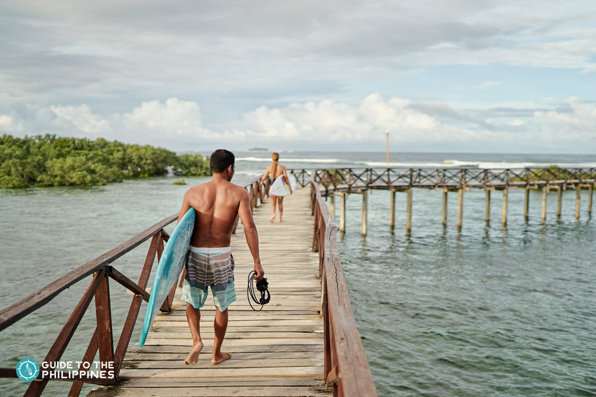 Surfer walking along the Cloud 9 boardwalk in Siargao Island.