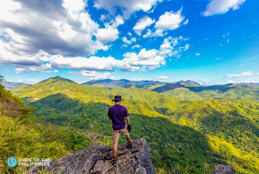 Hiker on a rock formation overlooking a lush mountain view Hiker on a rock formation overlooking a lush mountain view