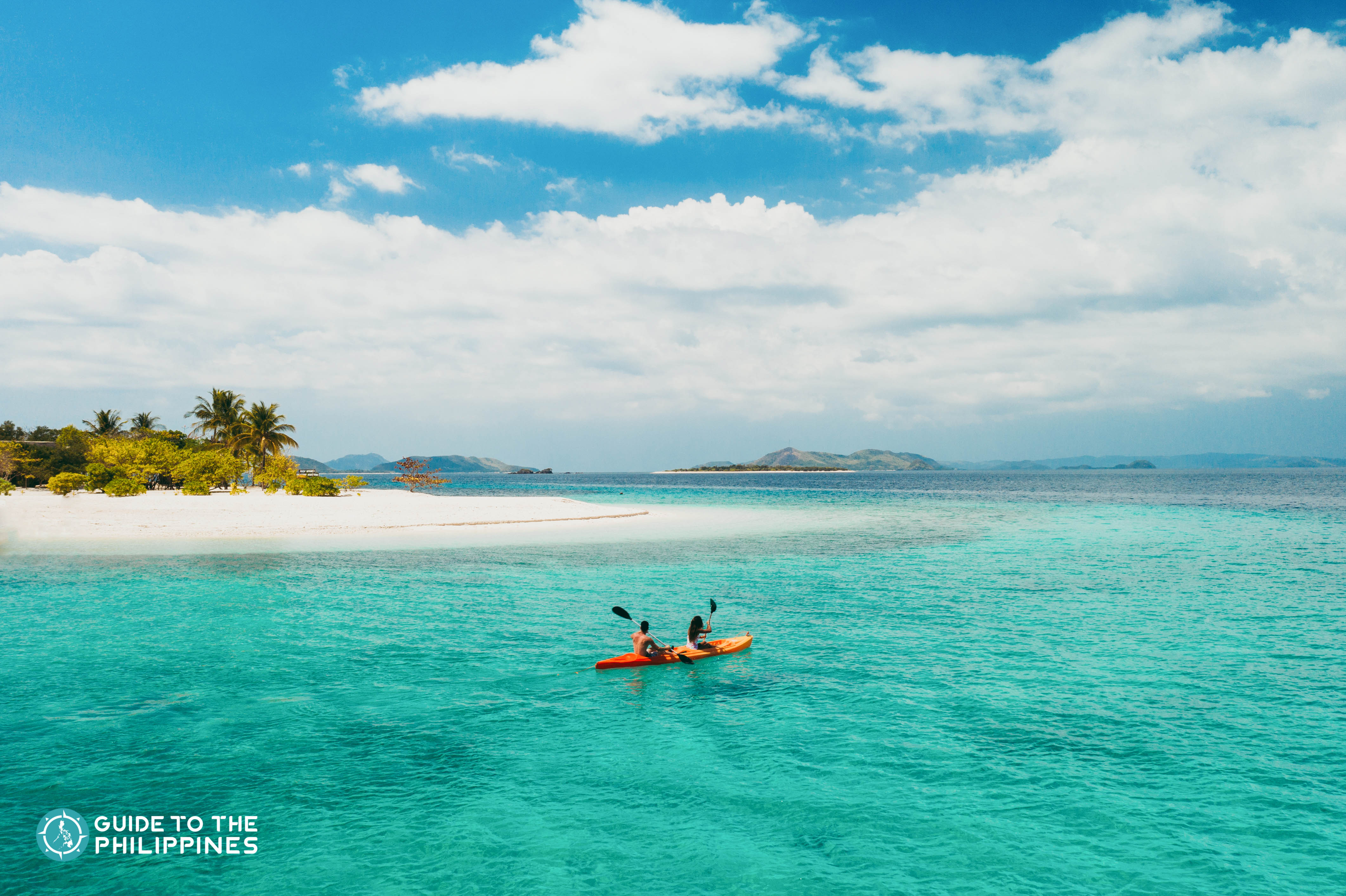Couple kayaking beside an island in the Philippines