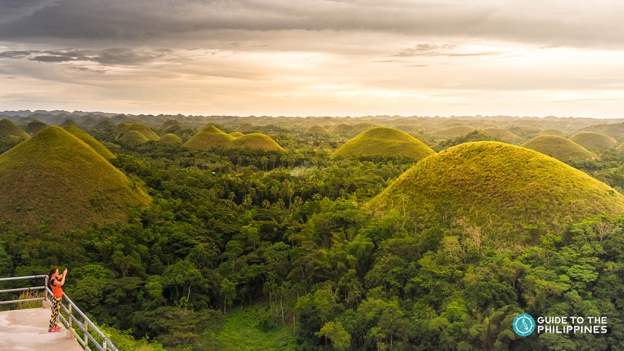 Traveler taking a photo from the Chocolate Hills Complex Viewpoint in Carmen, Bohol Traveler taking a photo from the Chocolate Hills Complex Viewpoint in Carmen, Bohol