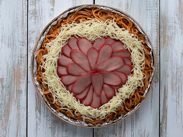 Pinoy-style spaghetti topped with hotdogs and cheese Pinoy-style spaghetti topped with hotdogs and cheese