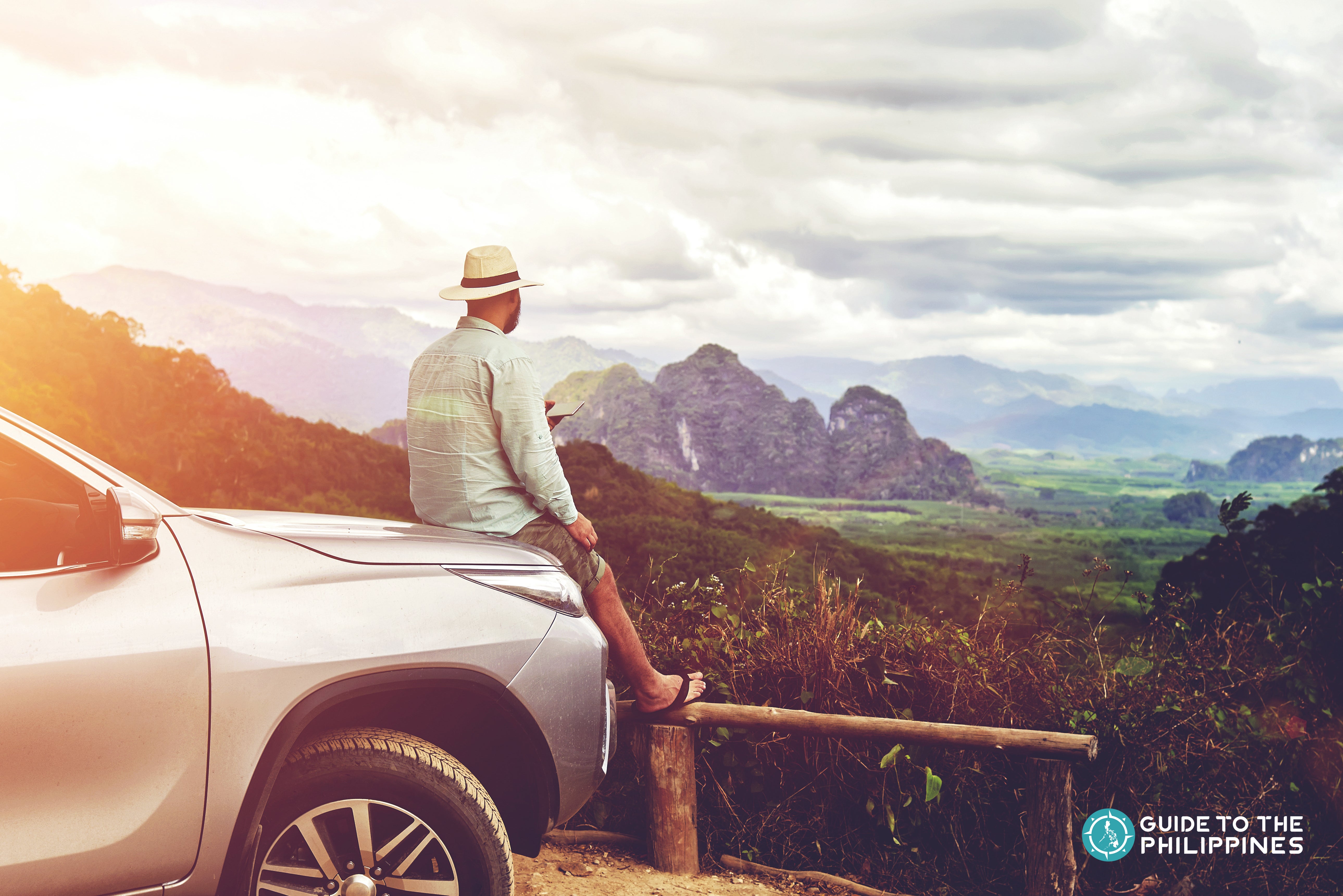 Staring at the roadside view while sitting on a car