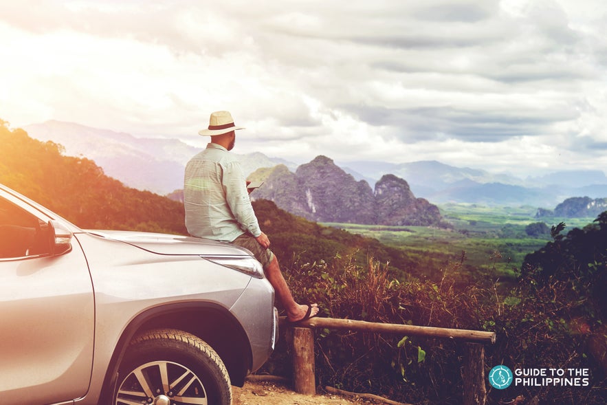 Staring at the roadside view while sitting on a car Staring at the roadside view while sitting on a car