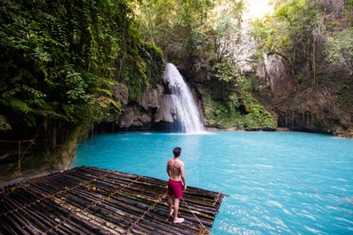 A man standing on a raft in Kawasan Falls