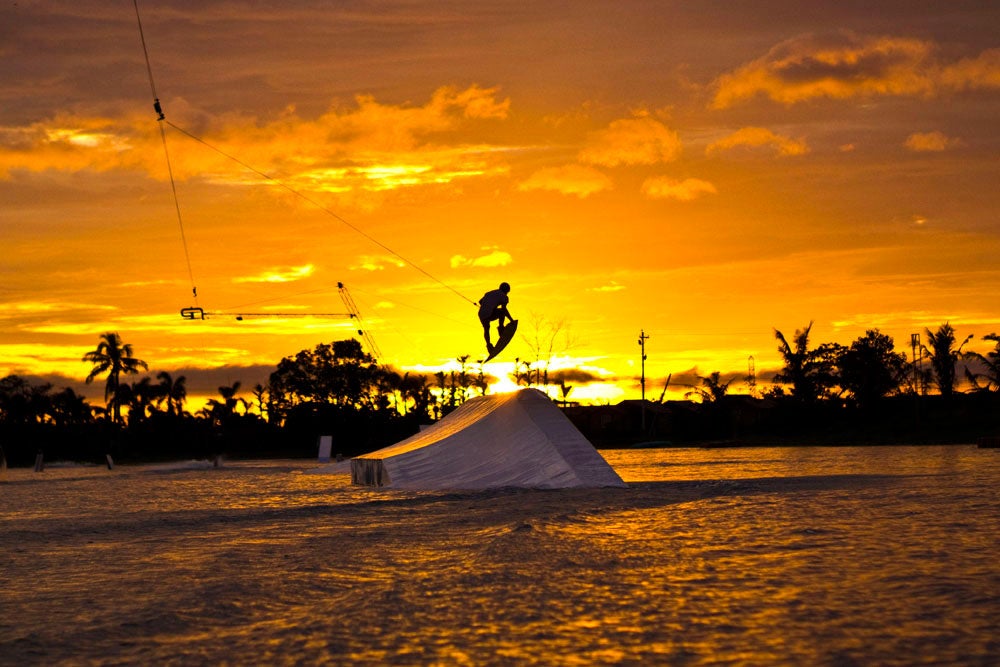 An athlete wakeboarding in CamSur Waterpark during sunset
