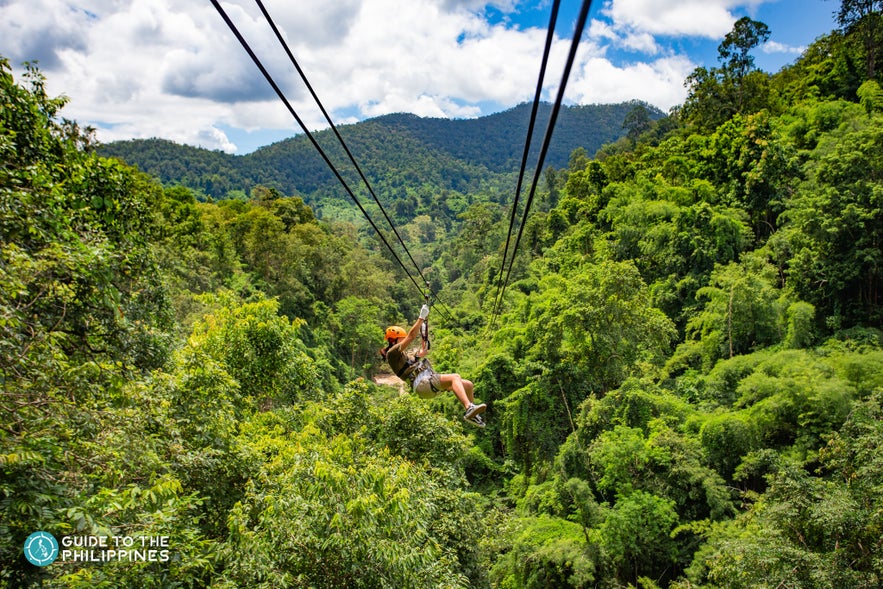 Woman ziplines above trees in a forest Woman ziplines above trees in a forest