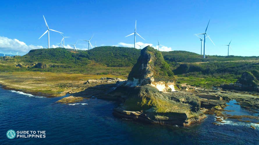 Kapurpurawan Rock Formation with the view of Bangui Windmills