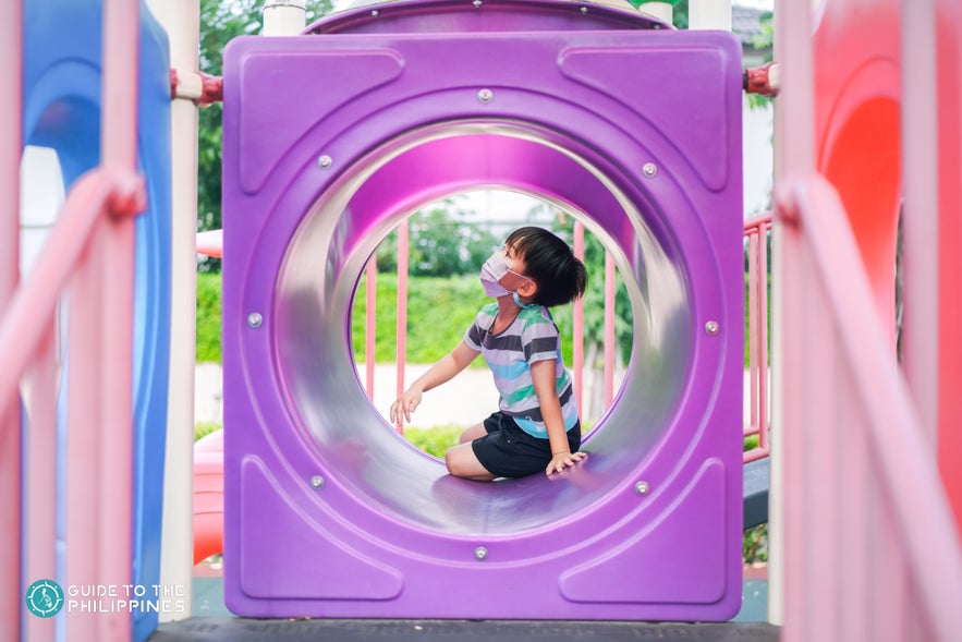 Boy with face mask plays in playground Boy with face mask plays in playground