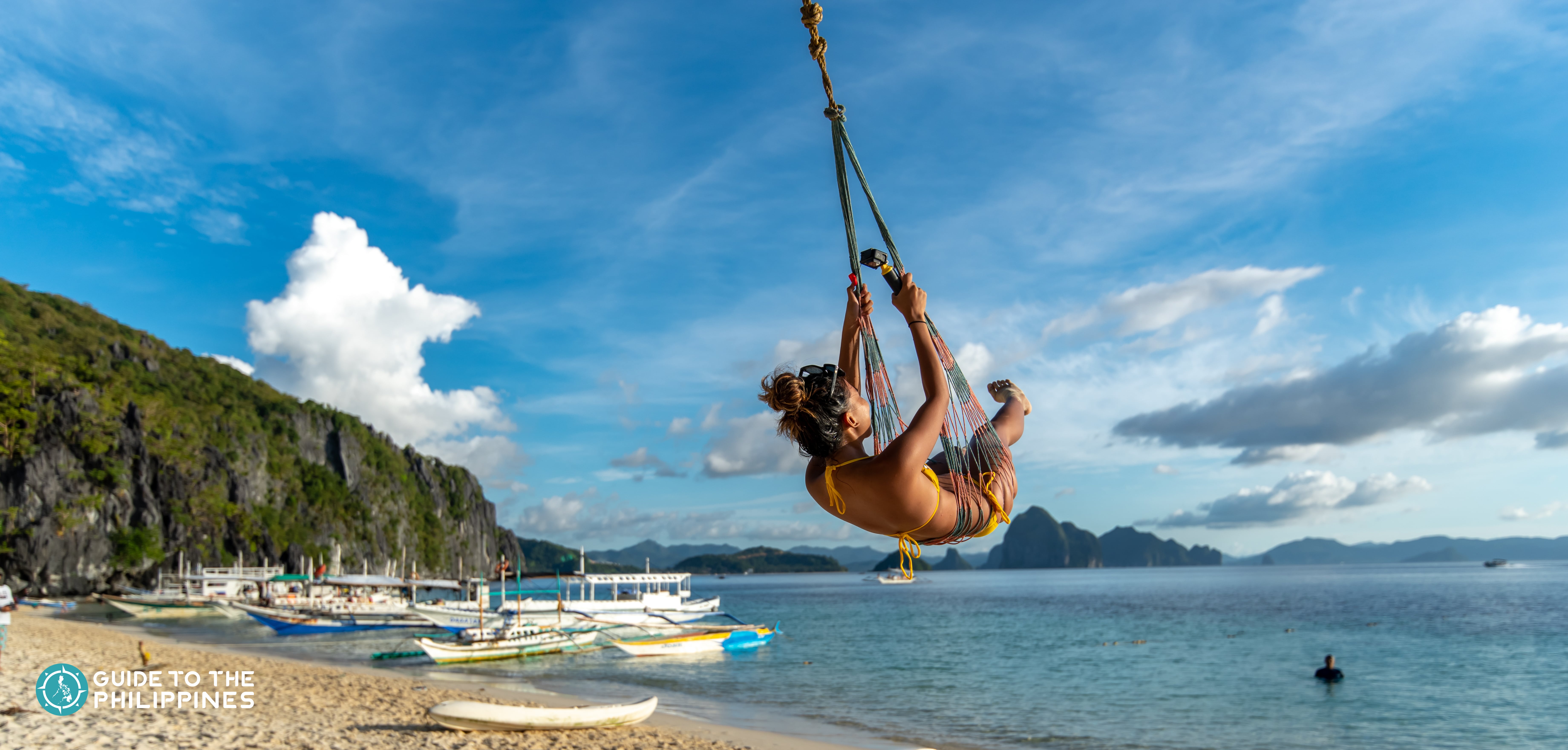 A girl enjoying a swing in Seven Commandos Beach in El Nido Palawan