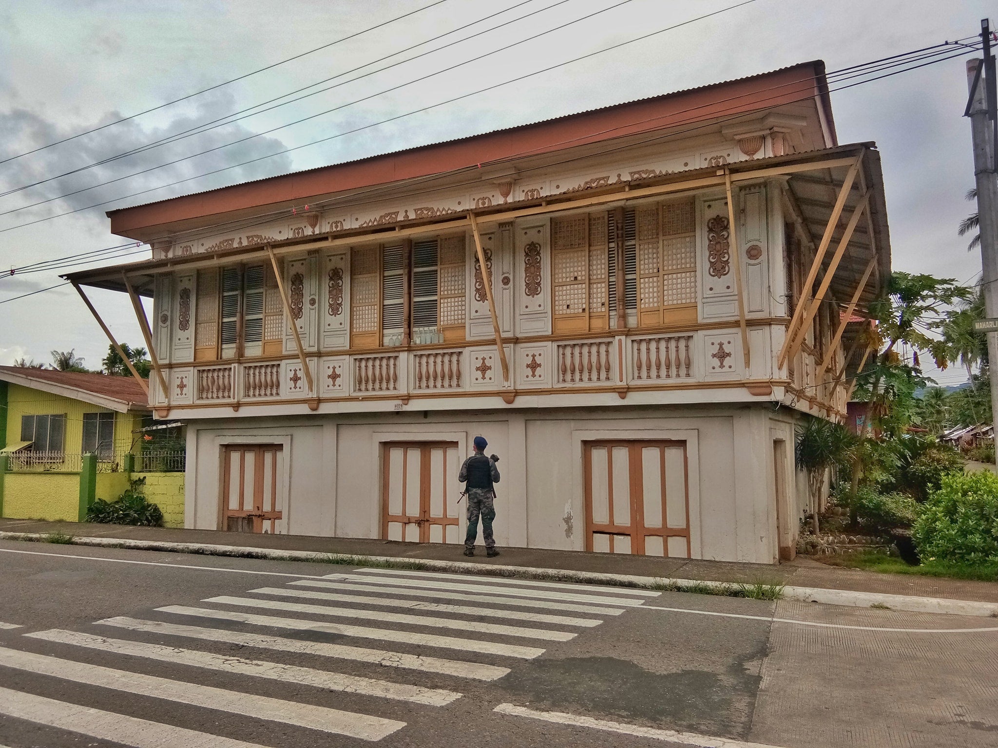 Guard stands infront of a bahay na bato in Juban