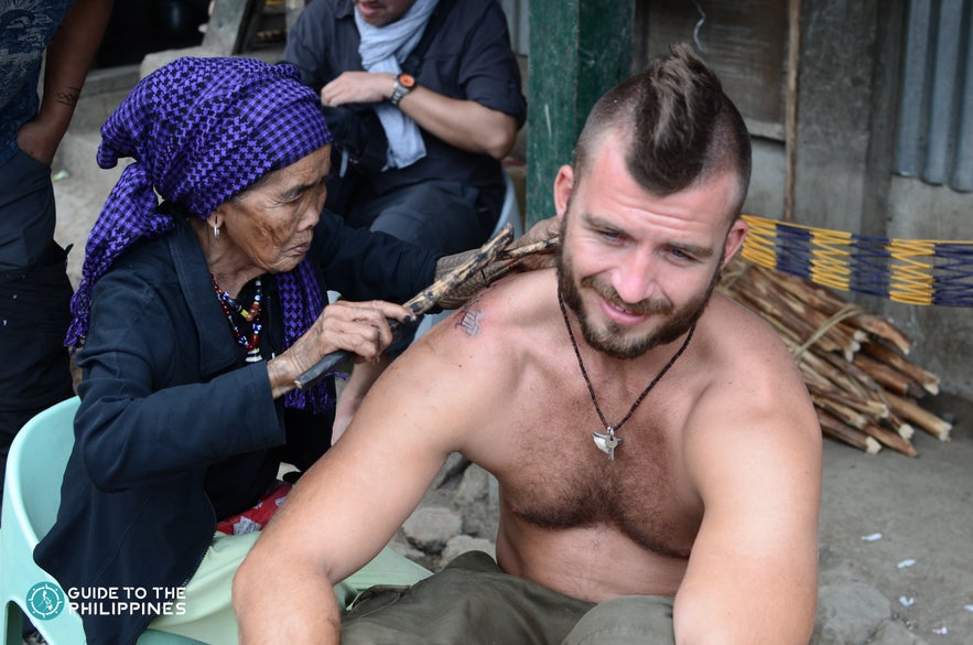 Apo Whang-Od creating a tattoo on a tourist in Buscalan Village Apo Whang-Od creating a tattoo on a tourist in Buscalan Village