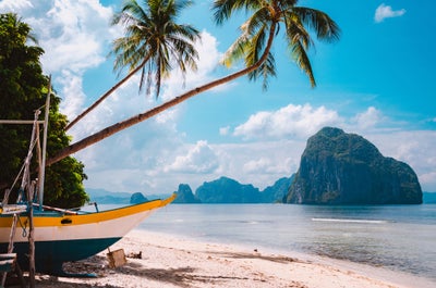 Banca boat on shore under palm trees.Tropical island scenic landscape. El-Nido, Palawan