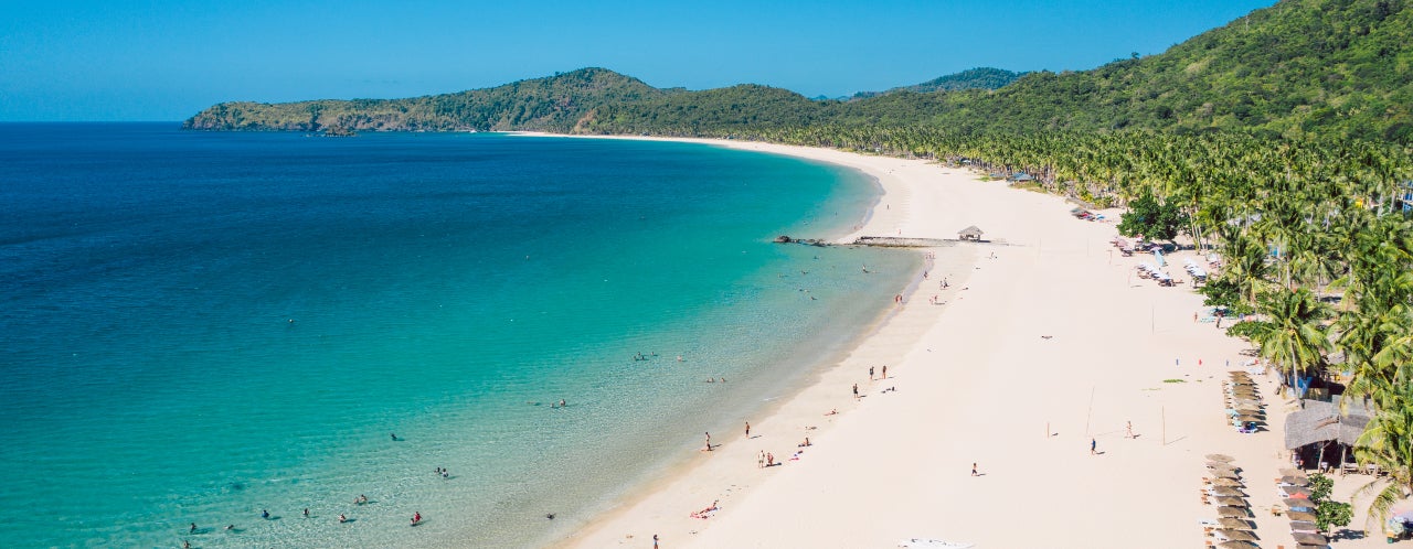 Long stretches of white sand and blue waters define the untouched beauty of Nacpan Beach, one of the stops on this tour in El Nido town