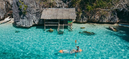 Man kayaking in the twin lagoon between the rocks and fishermen houses in Coron, Palawan