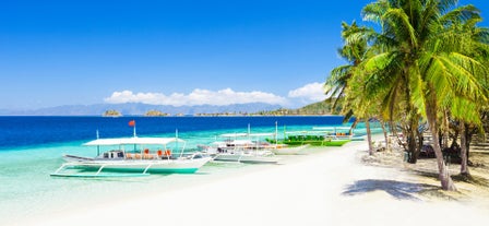 Numerous boats docked on a powdery white sand beach during this island hopping tour in Boracay.