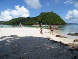 Tourists enjoying the serene beauty of Pamuayan Beach as part of the Port Barton village island hopping tour