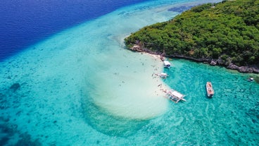 Aerial view of sandy beach with tourists swimming in beautiful clear sea water of the Sumilon island beach landing near Oslob, Cebu, Philippines