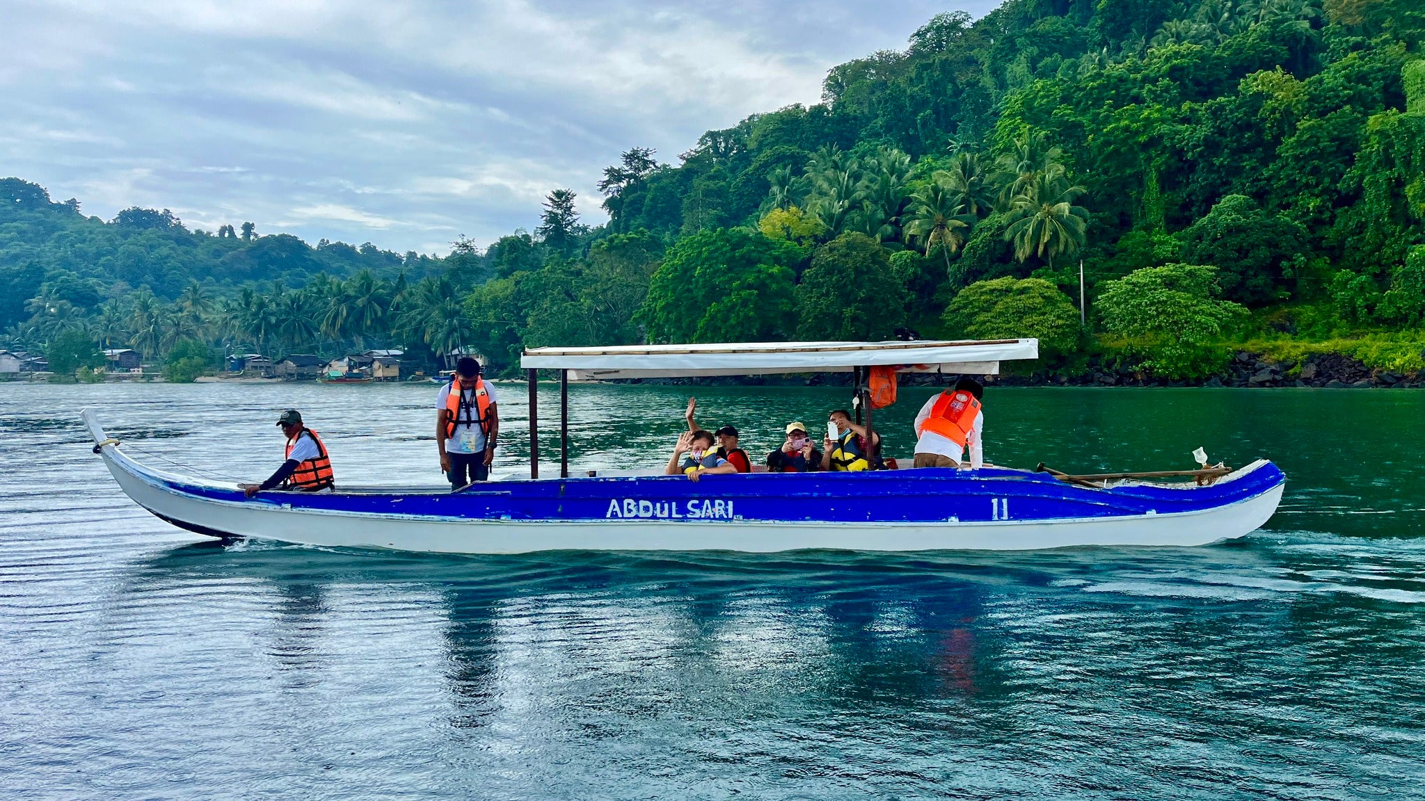 A wooden boat carrying tourists approaches a lush shore on this private Once Islas Islands tour in Zamboanga City.