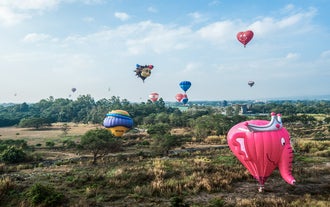 Wide aerial view of many unique hot air balloons floating over the grounds with this ticket to Philippine International Hot Air Balloon Festival in New Clark City.