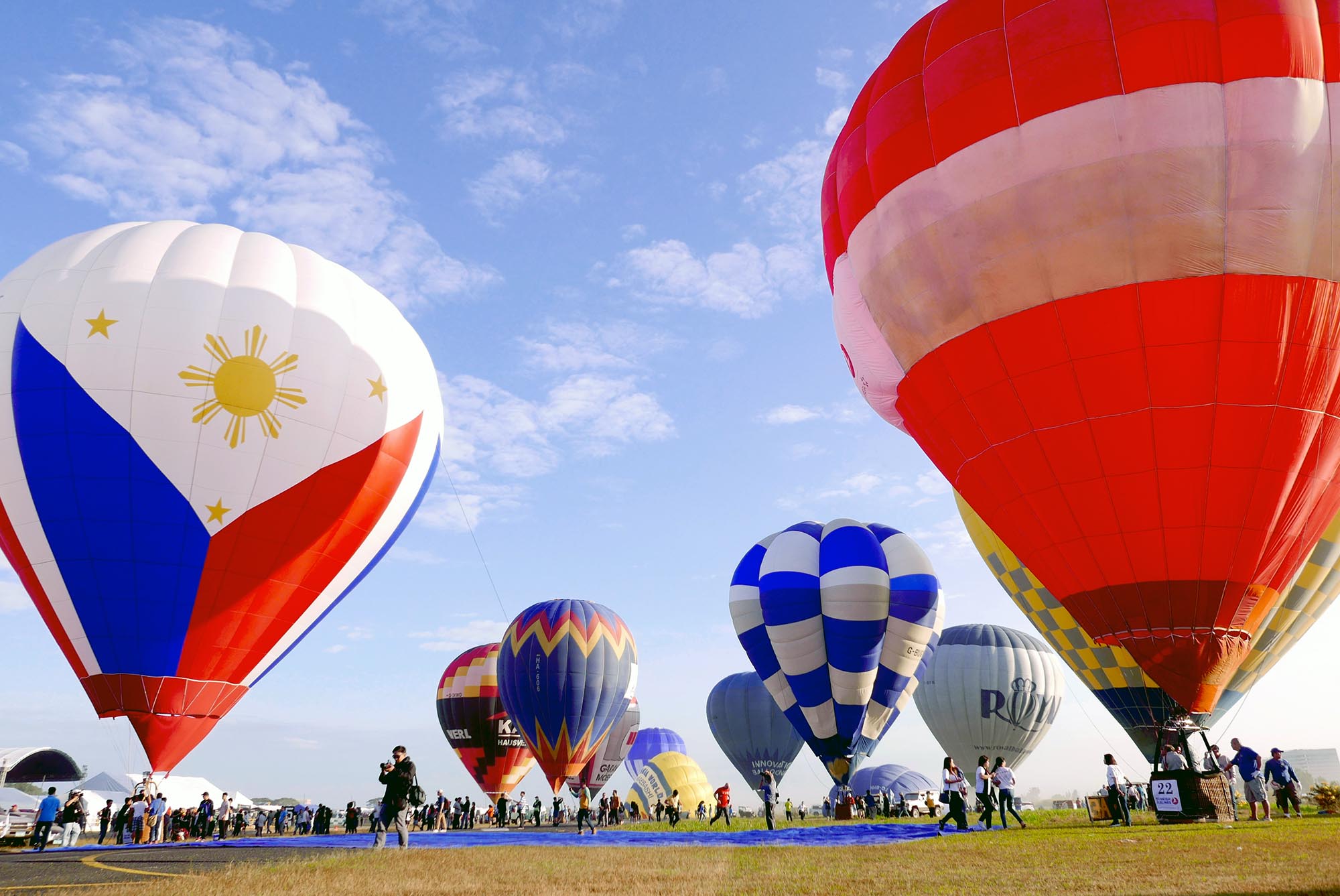 Massive, partially inflated hot air balloons stand on the field, ready for liftoff during this 2-day festival Package in New Clark City.