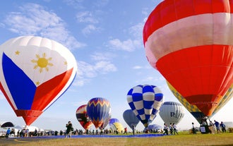 Massive, partially inflated hot air balloons stand on the field, ready for liftoff during this 2-day festival Package in New Clark City.