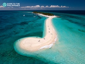A scenic view of the crystal-clear waters and white sandy shores during a Kalanggaman Island tour in Leyte Province.