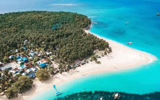 Enjoy this Siargao Island day tour to Daku Island, showcasing its wide white-sand beach and blue waters