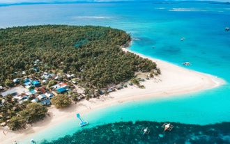 Enjoy this Siargao Island day tour to Daku Island, showcasing its wide white-sand beach and blue waters