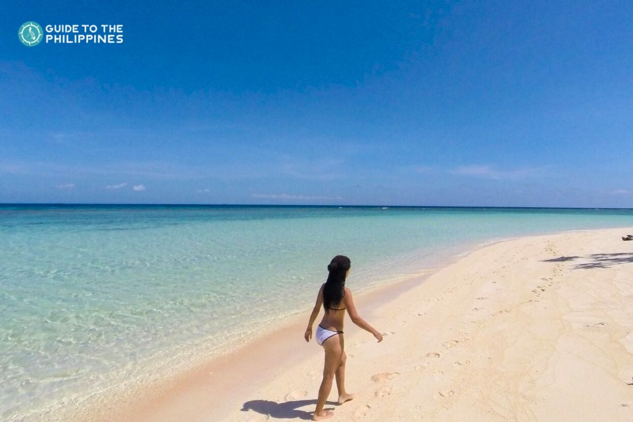 A traveler enjoying a serene stroll along one of the uncrowded white sand beaches of Balabac town in Palawan Province.