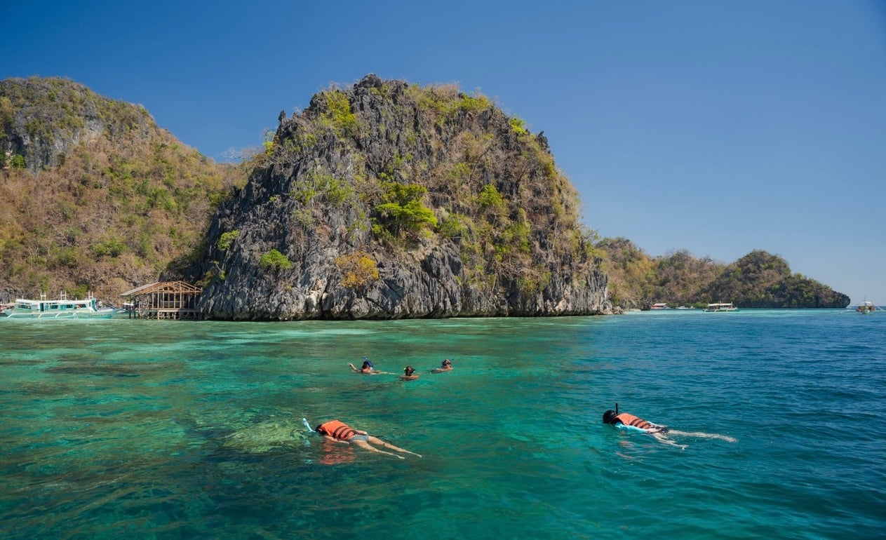 Tourists snorkeling at one of the vibrant reef stops during this Coron Island hopping party boat tour