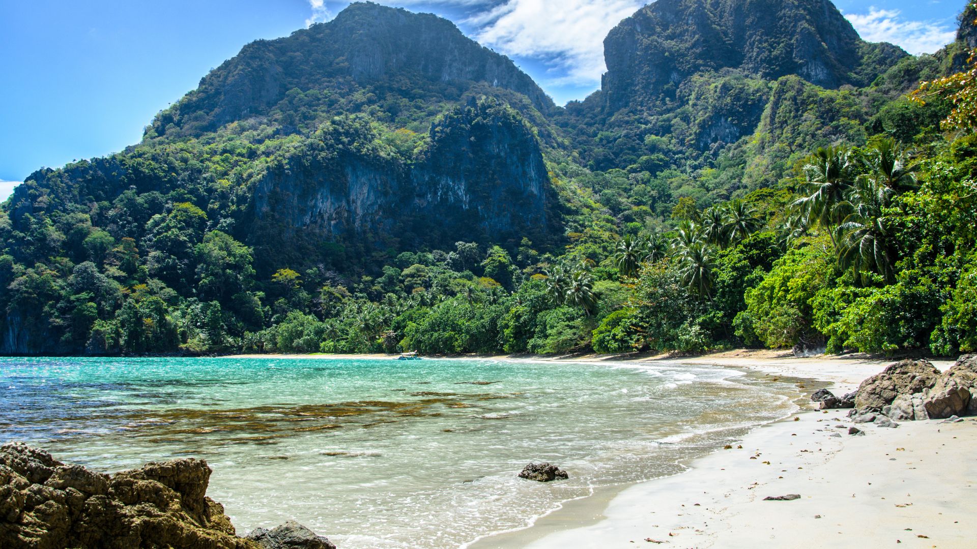 A serene view of Cadlao Lagoon, where golden sand meets rugged rock formations, making for a breathtaking stop on this island hopping tour D in El Nido town