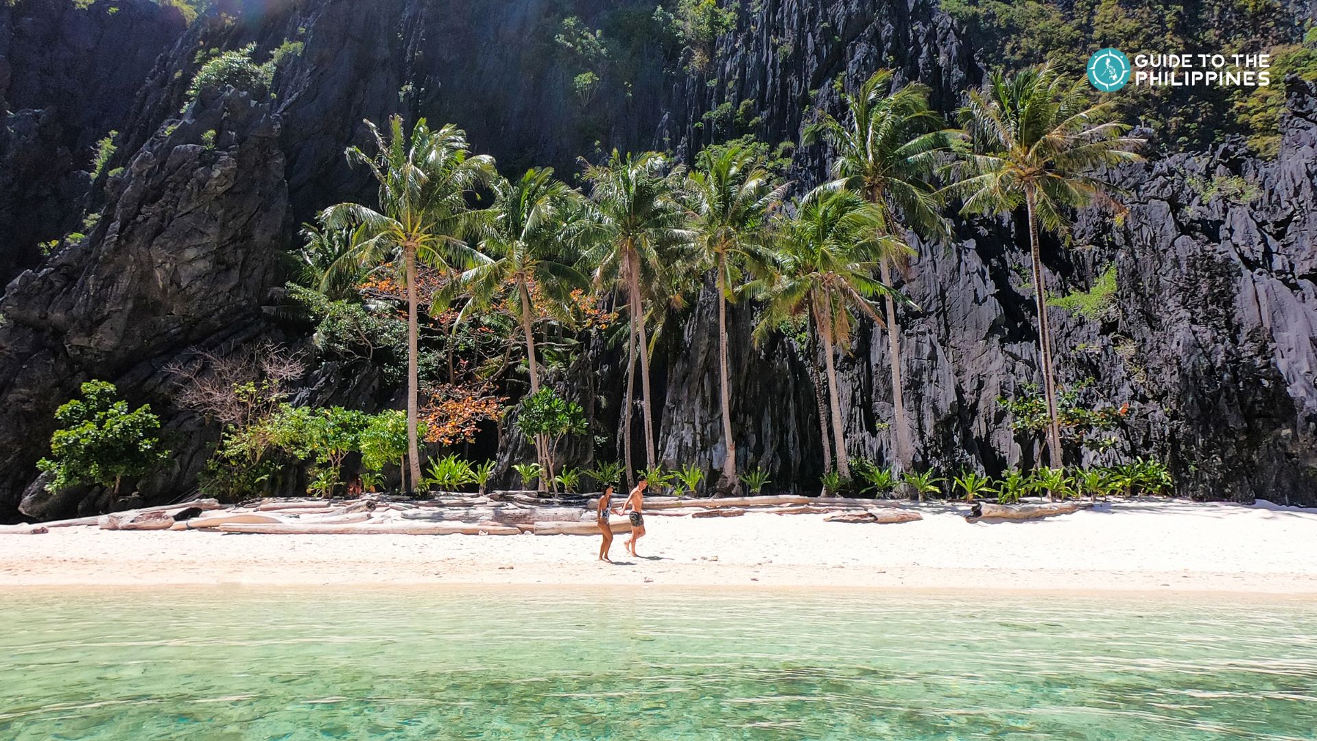 A couple walking along a white sand beach on an island in El Nido, Palawan