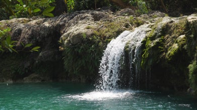 A stunning view of Bolinao Falls cascading into a crystal-clear pool, a perfect spot for swimming and cliff jumping during this Pangasinan Province tour package