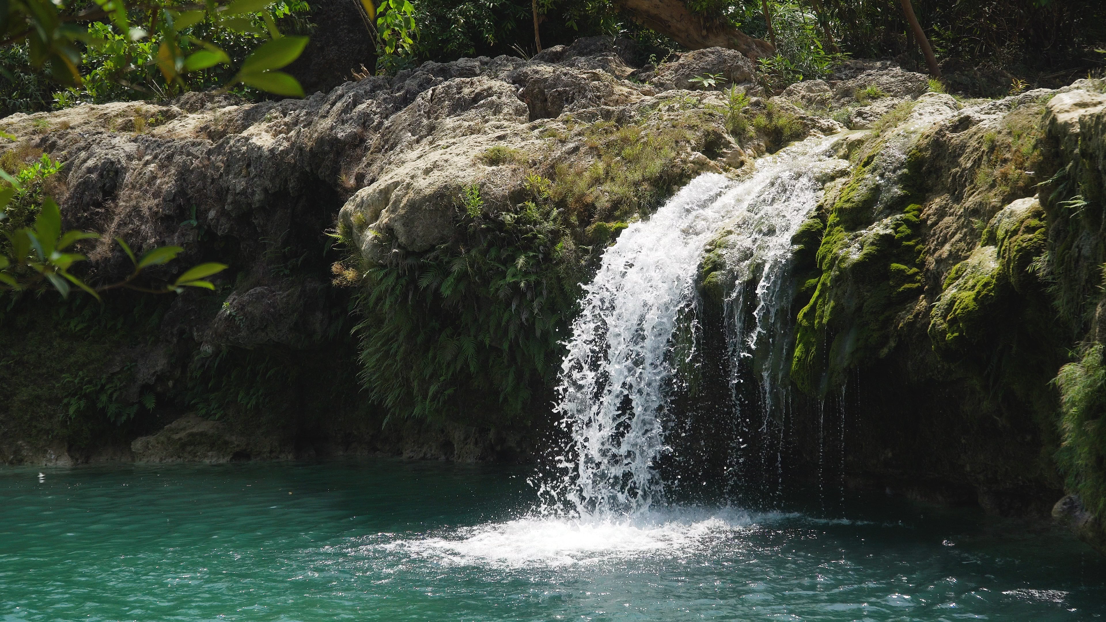 A stunning view of Bolinao Falls cascading into a crystal-clear pool, a perfect spot for swimming and cliff jumping during this Pangasinan Province tour package