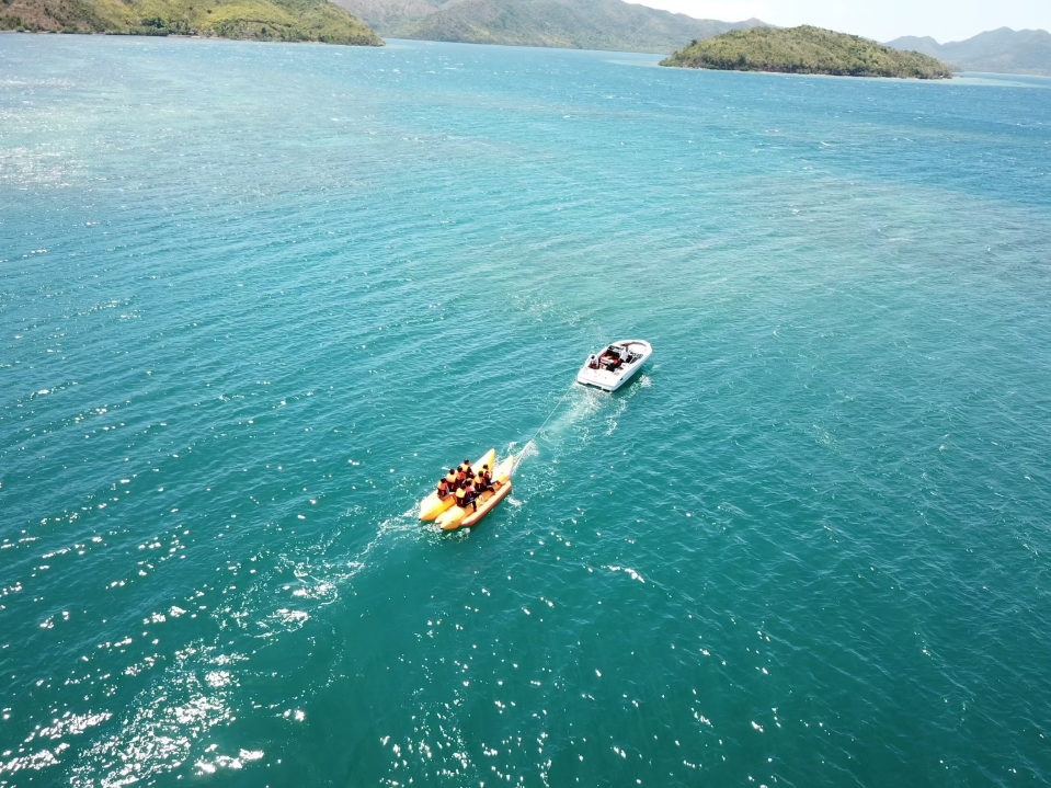 Adventurers gliding over waves on a banana boat in Coron town