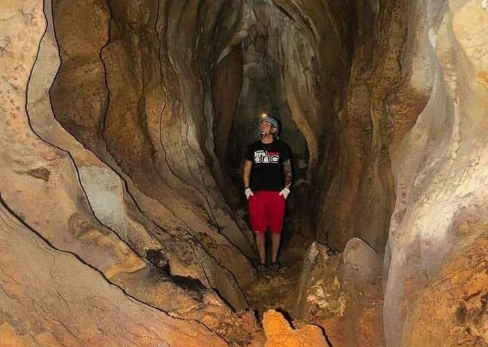 A solo adventurer pauses for breath, illuminated by cave light on a steep path during this tour in Puerto Princesa City.