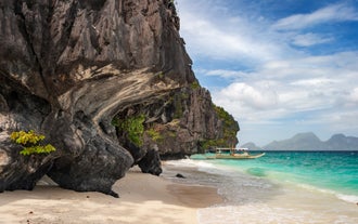 The pristine white sand beach and blue waters of Entalula Island is part of your tour package at El Nido town.