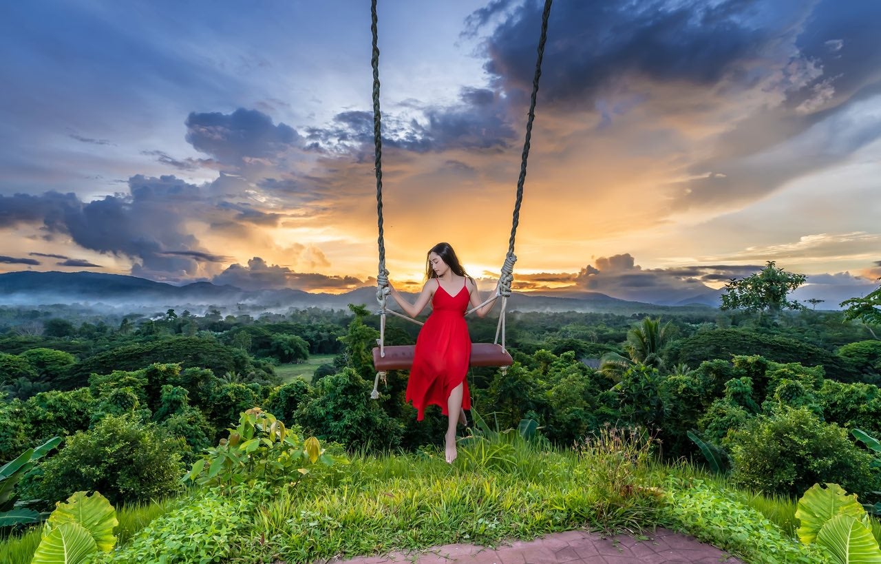 A visitor enjoying the Jungle Swing with panoramic hillside views at this Palawan photo theme park.