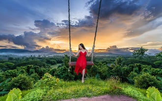 A visitor enjoying the Jungle Swing with panoramic hillside views at this Palawan photo theme park.