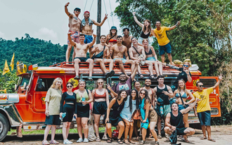 A group of travelers posing for photos beside a colorful jeepney on this fun tour in El Nido town