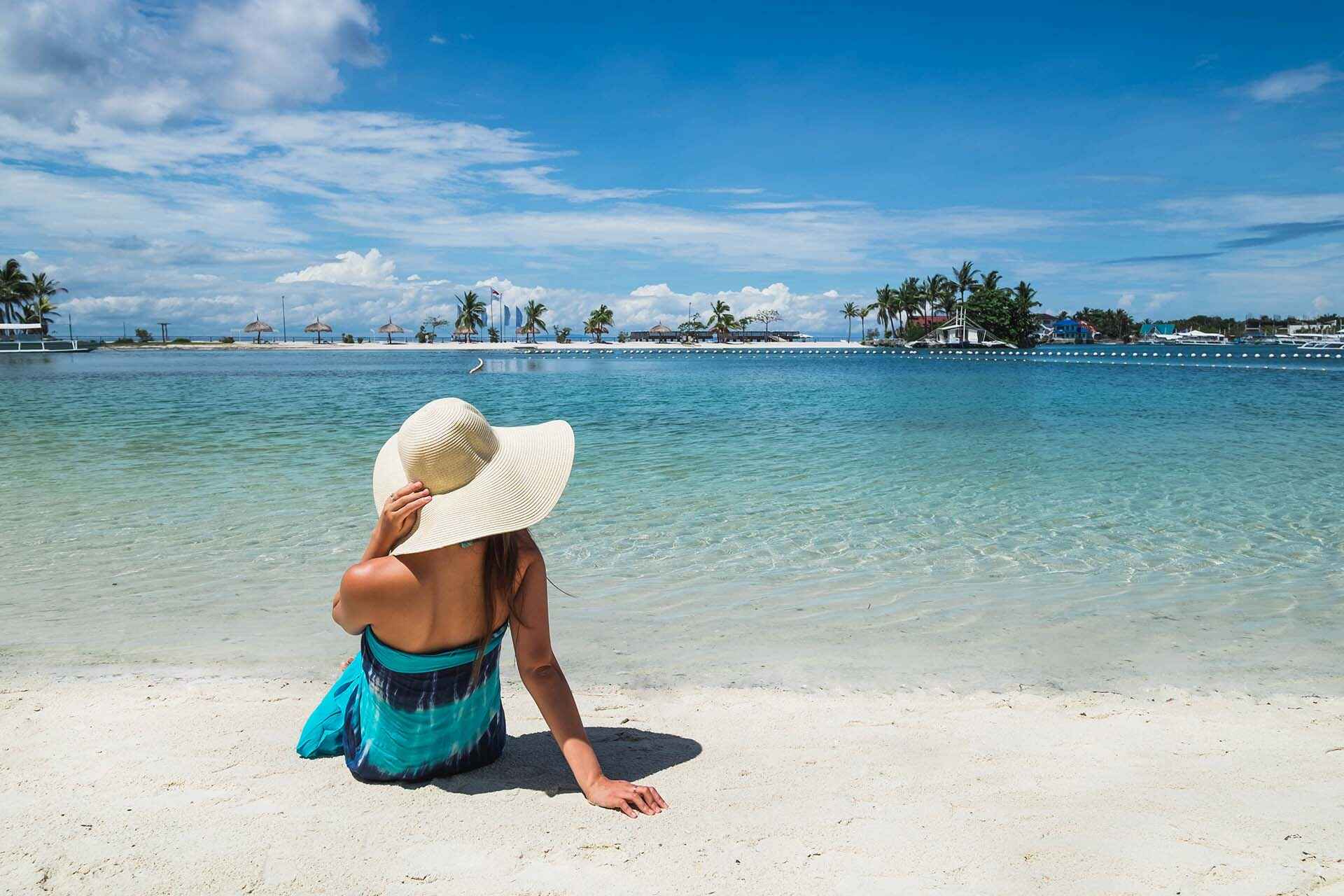 A traveler lounging on a white sand beach on Mactan Island.