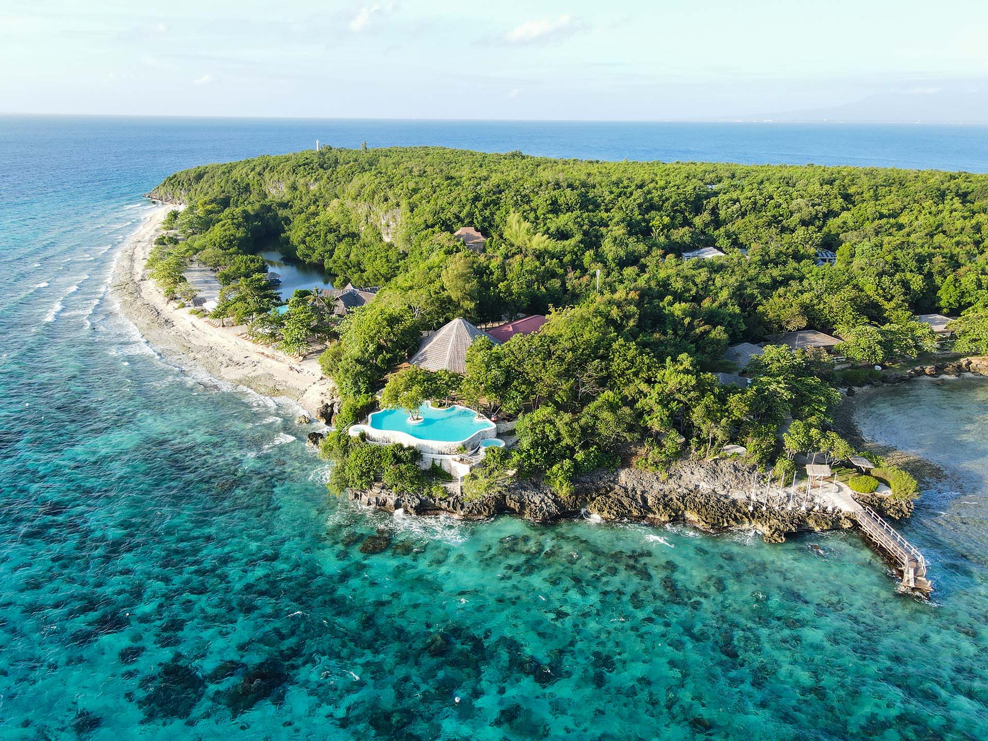 An aerial view of Bluewater Sumilon Island Resort, showcasing its turquoise waters, lush greenery, and inviting beachfront villas.